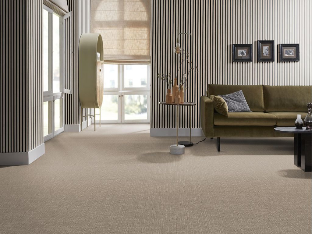 Woonkamer met houten wandpanelen, groene bank en beige tapijt die mooi op elkaar aansluiten