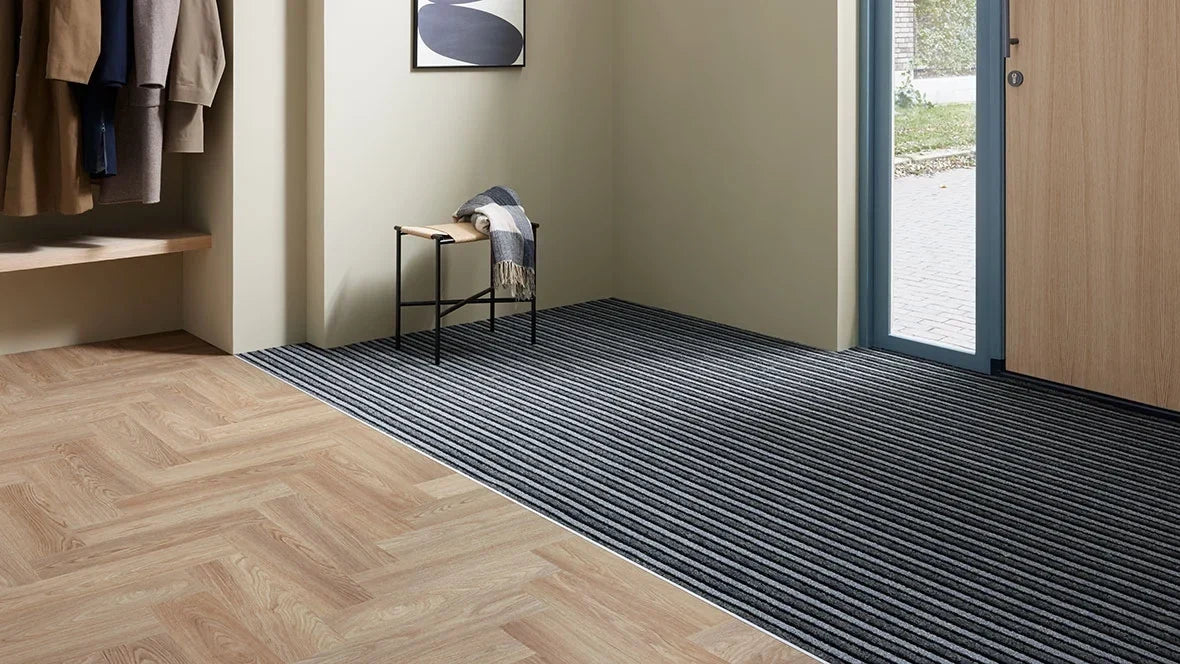Entree met Coral schoonloopmat van Forbo bij de voordeur, visgraatvloer en kapstok