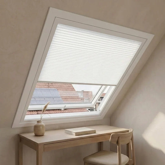 Dakraam met lichte plissé, houten bureau en stoel in een zolderkamer in Japandi-stijl