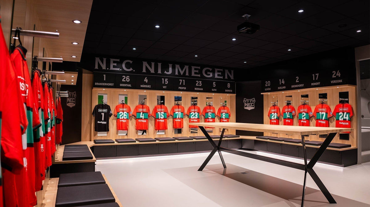 Kleedkamer van N.E.C. Nijmegen met rood-groene shirts, houten kasten en lichte vloer