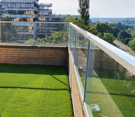 Balkon met kunstgras, glazen balustrade en uitzicht over de stad