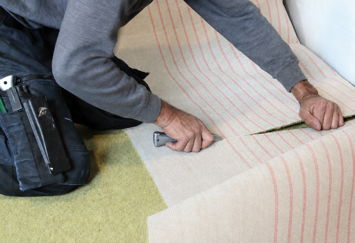 Stoffeerder van Hofmans at Home snijdt tapijt op maat met een tapijtmes