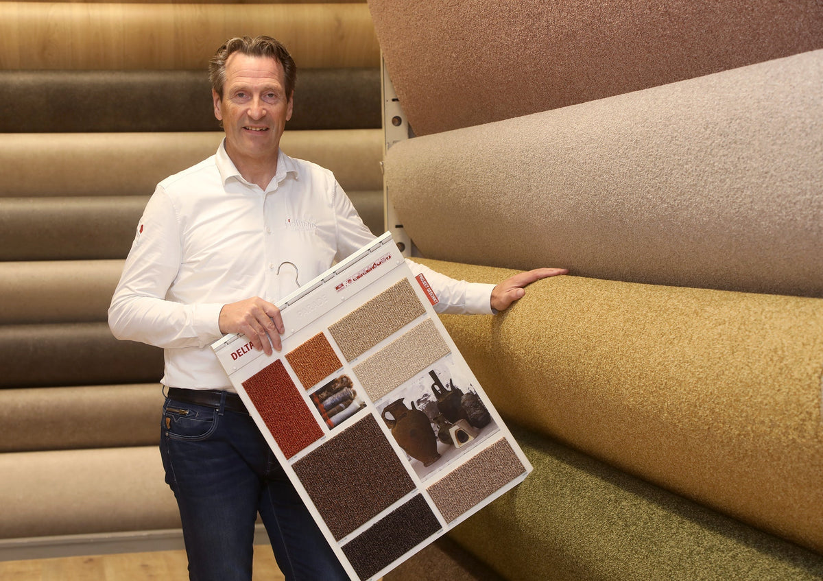 Tapijtadviseur Nico met tapijtstalen bij tapijtrollen in de showroom van Hofmans at Home