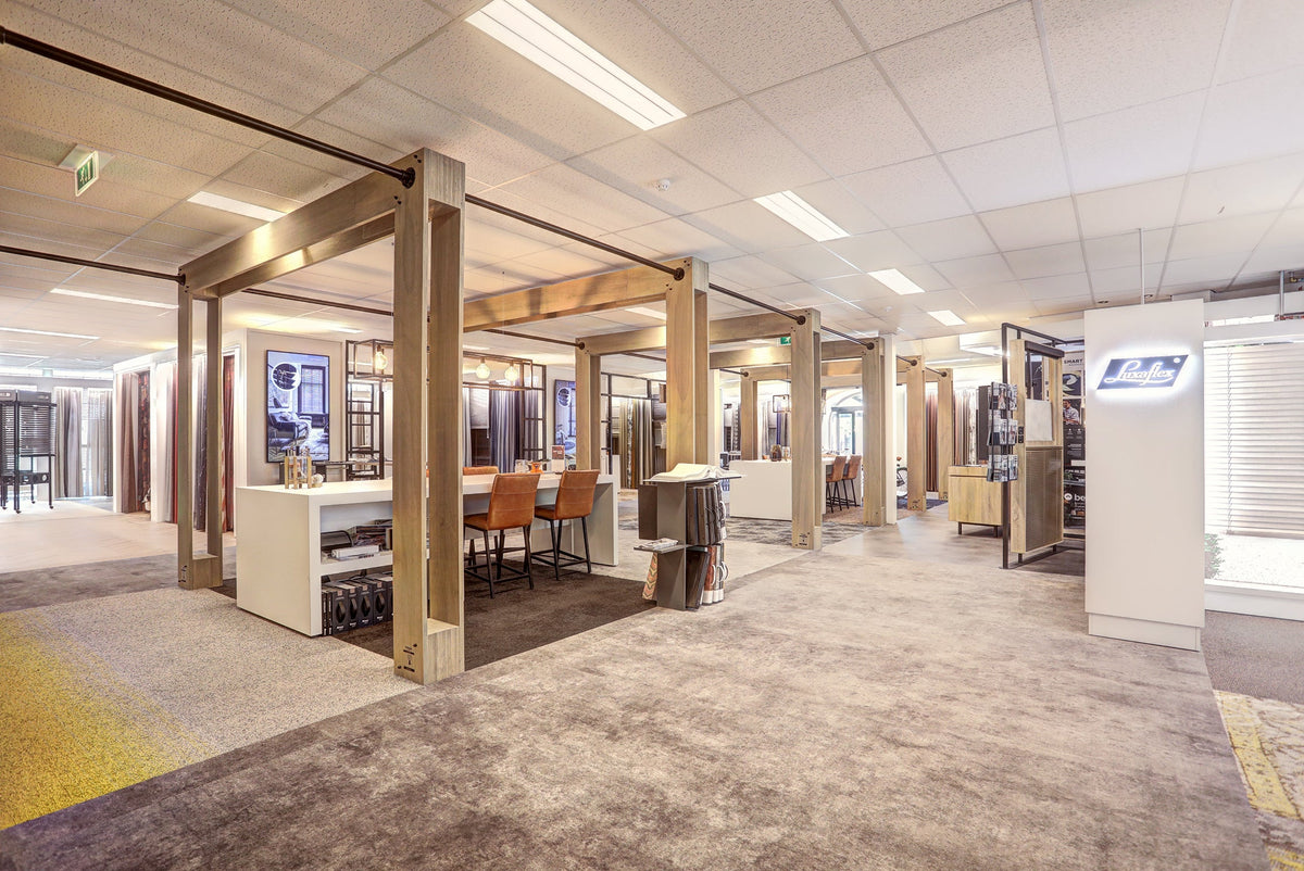 Showroom zonwering binnen bij Hofmans at Home met houten frames en stalentafels
