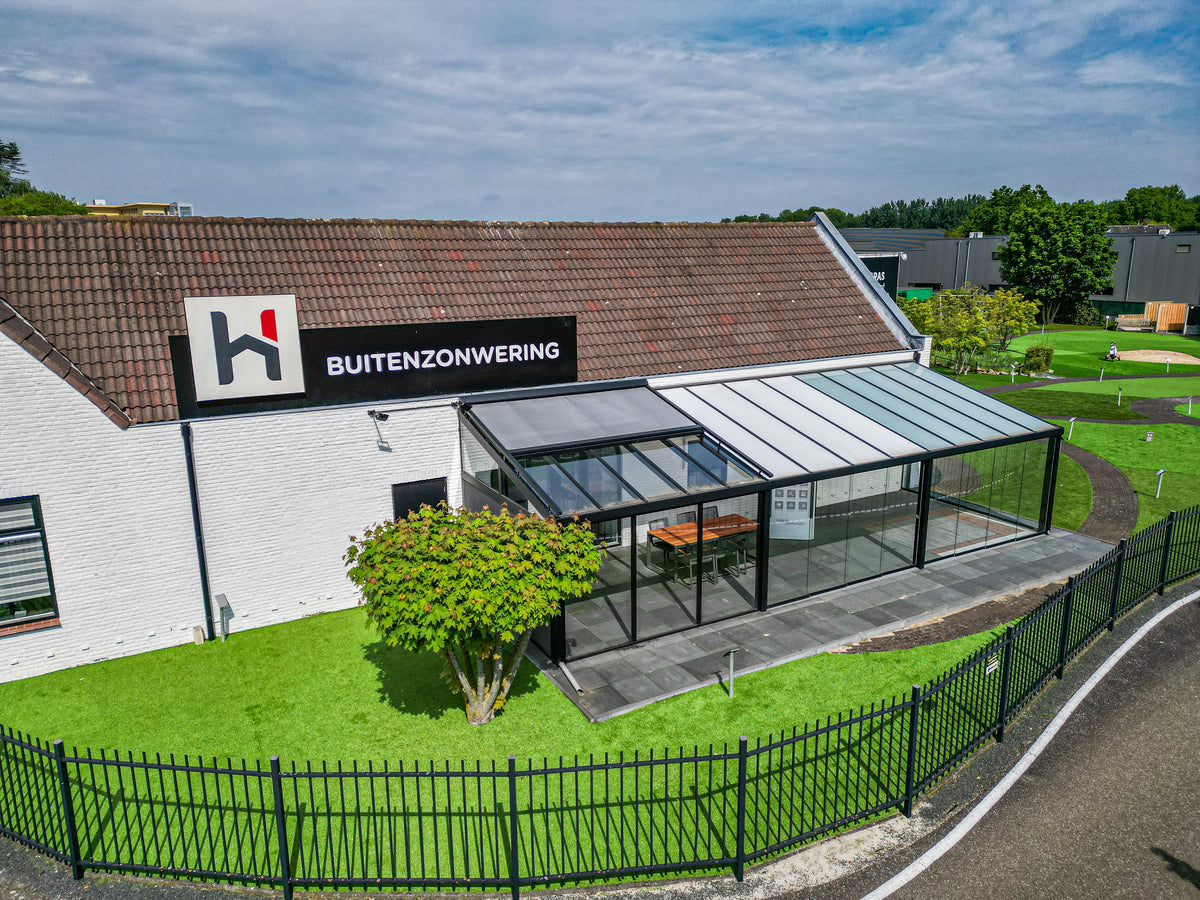Showtuin buitenzonwering van Hofmans at Home met glazen overkapping en kunstgras