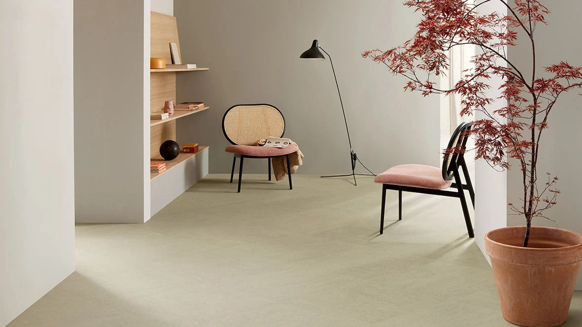 Ruimte met lichtgroene marmoleum vloer, roze stoelen en een Japanse esdoorn in pot