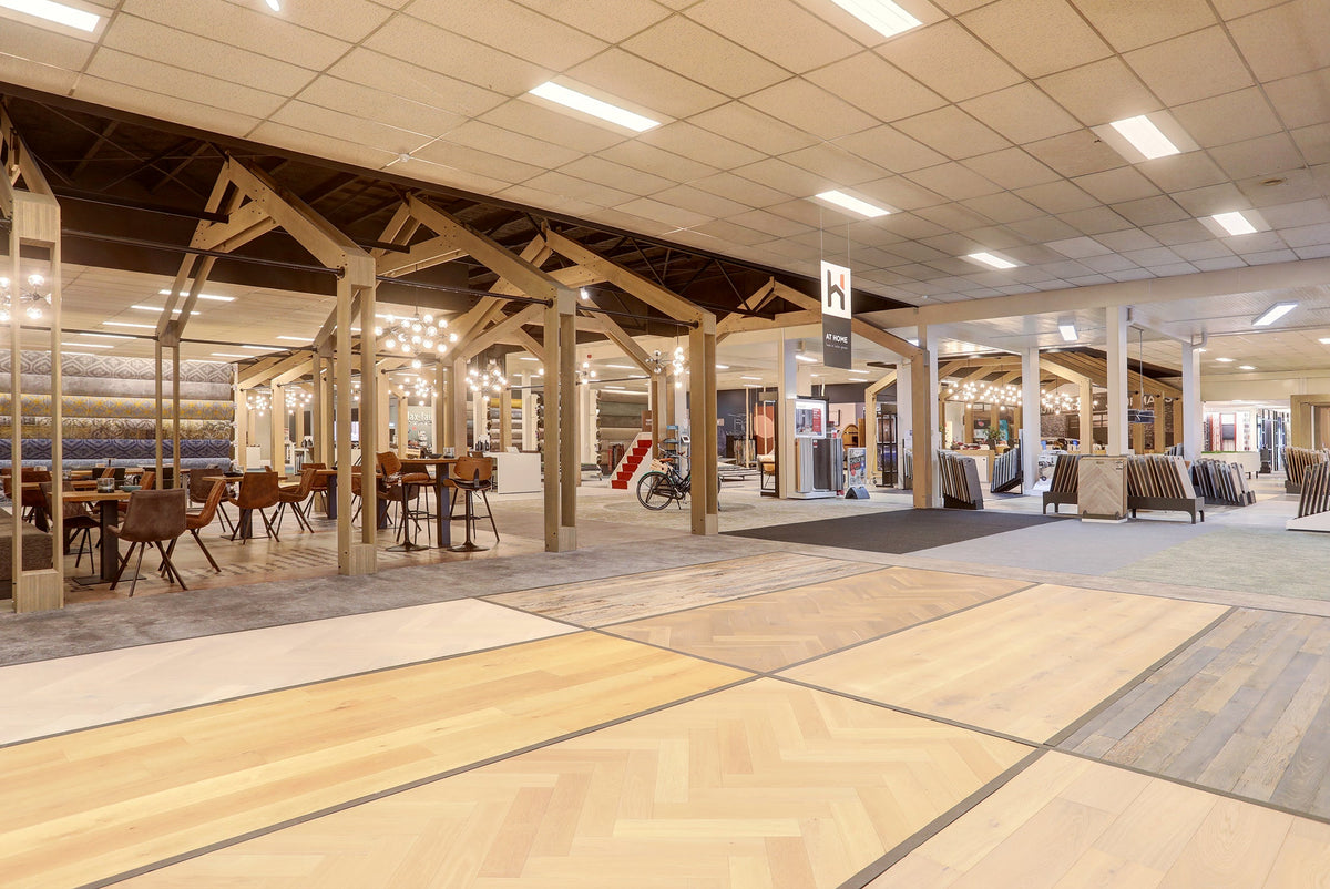 Parketvloeren en tapijt bij de koffiehoek in de grote showroom van Hofmans at Home