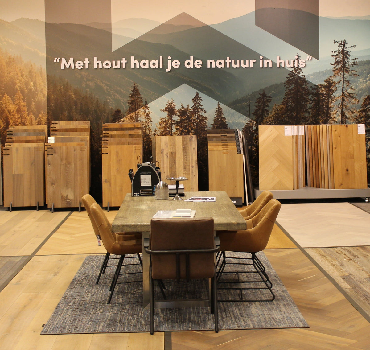 Houten vloeren in de showroom van Hofmans at Home met tafel en natuurbehang