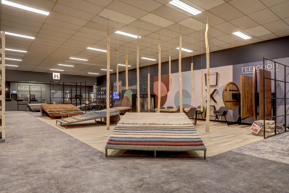 Vloerkledenafdeling in de showroom van Hofmans at Home met gestapelde kleden en presentaties