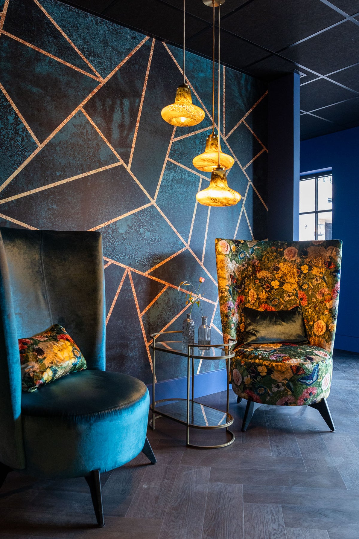 Lounge van Hotel De Bungelaer met blauw grafisch behang en fluwelen fauteuils
