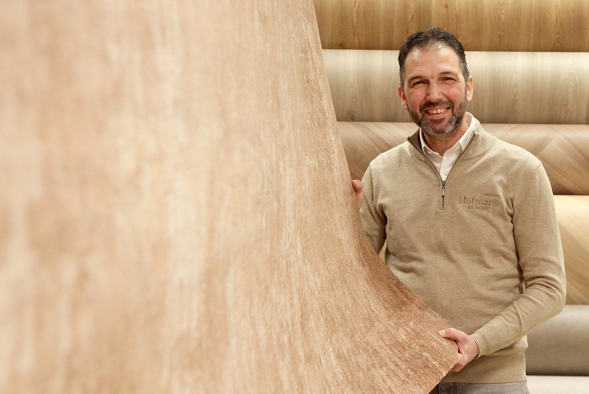 Adviseur Erik toont een baan vinyl in houtlook in de showroom van Hofmans at Home