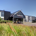 Gevel van Hofmans at Home in Cuijk met logo boven de entree en siergrassen op de voorgrond
