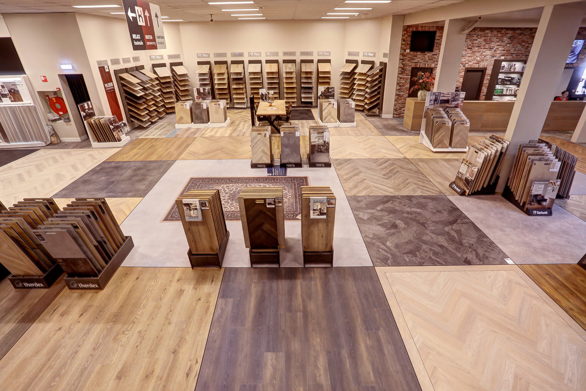 Ruime vloerenshowroom met PVC- en laminaatstalen en diverse vloeren op de grond bij Hofmans at Home