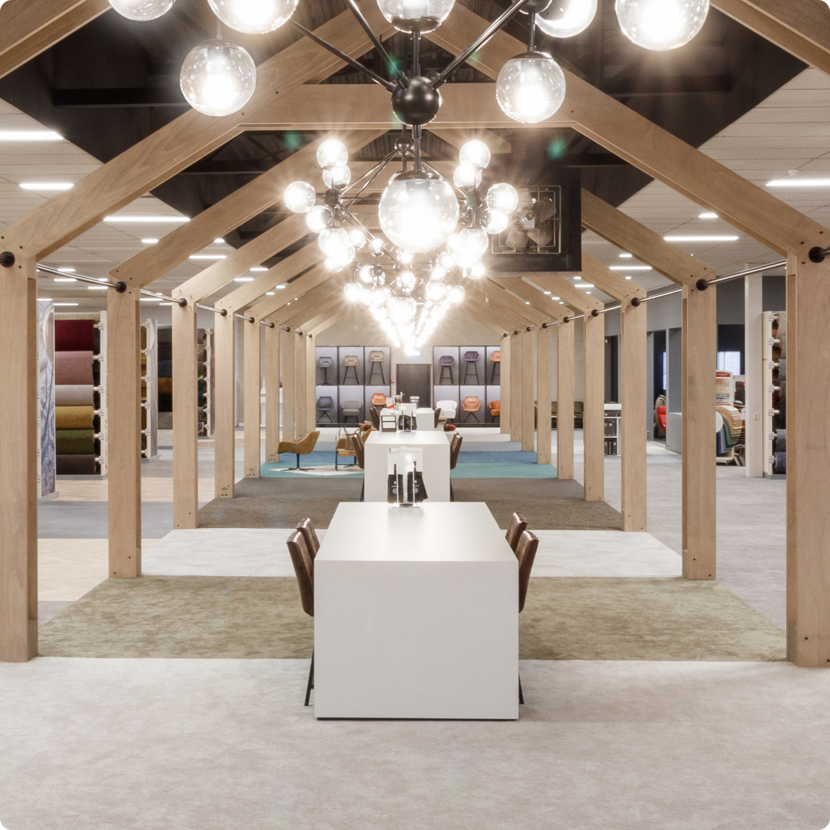 Showroom van Hofmans at Home met houten spanten, bollampen en vloerkleden en tapijtstalen