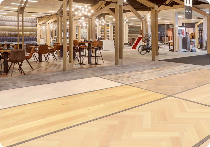 Showroom van Hofmans at Home met houten spanten, zithoek en verschillende visgraatvloeren