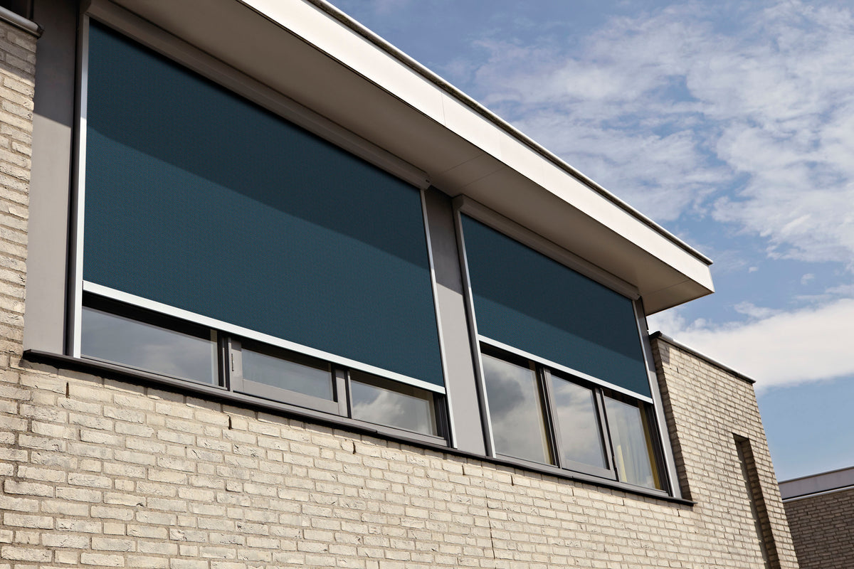 Moderne woning met donkerblauwe screens als buitenzonwering voor de ramen