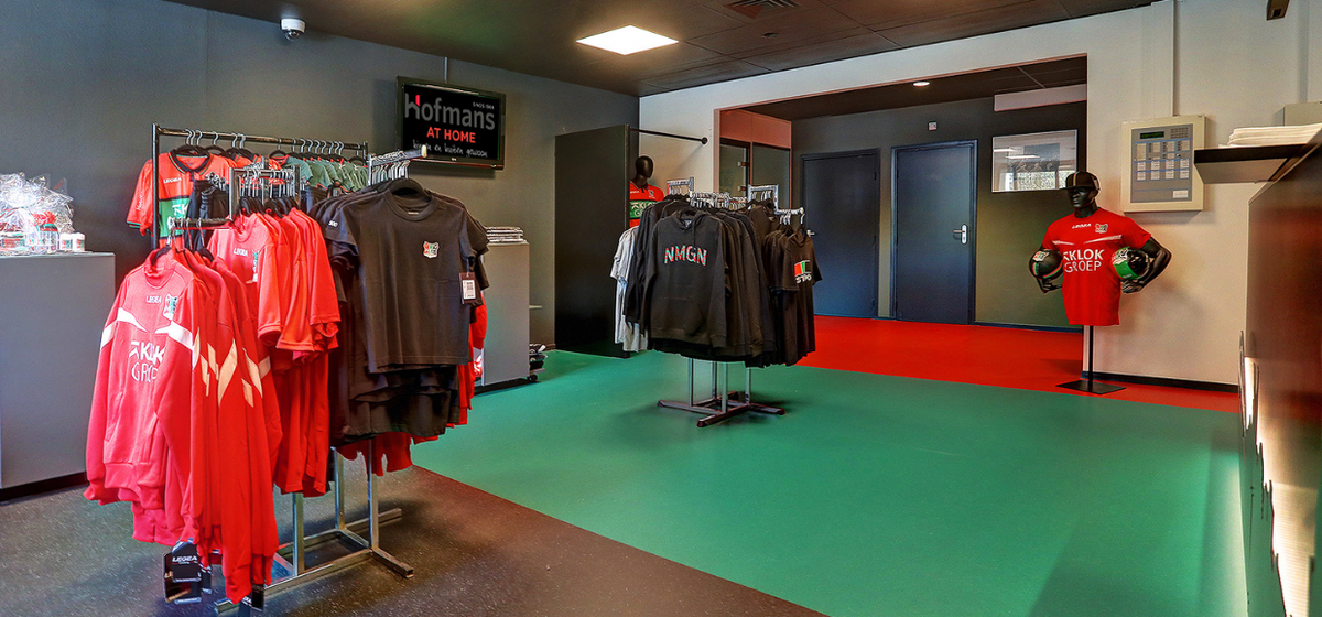 Fanshop van N.E.C. met groene en rode vloer, kledingrekken en shirts