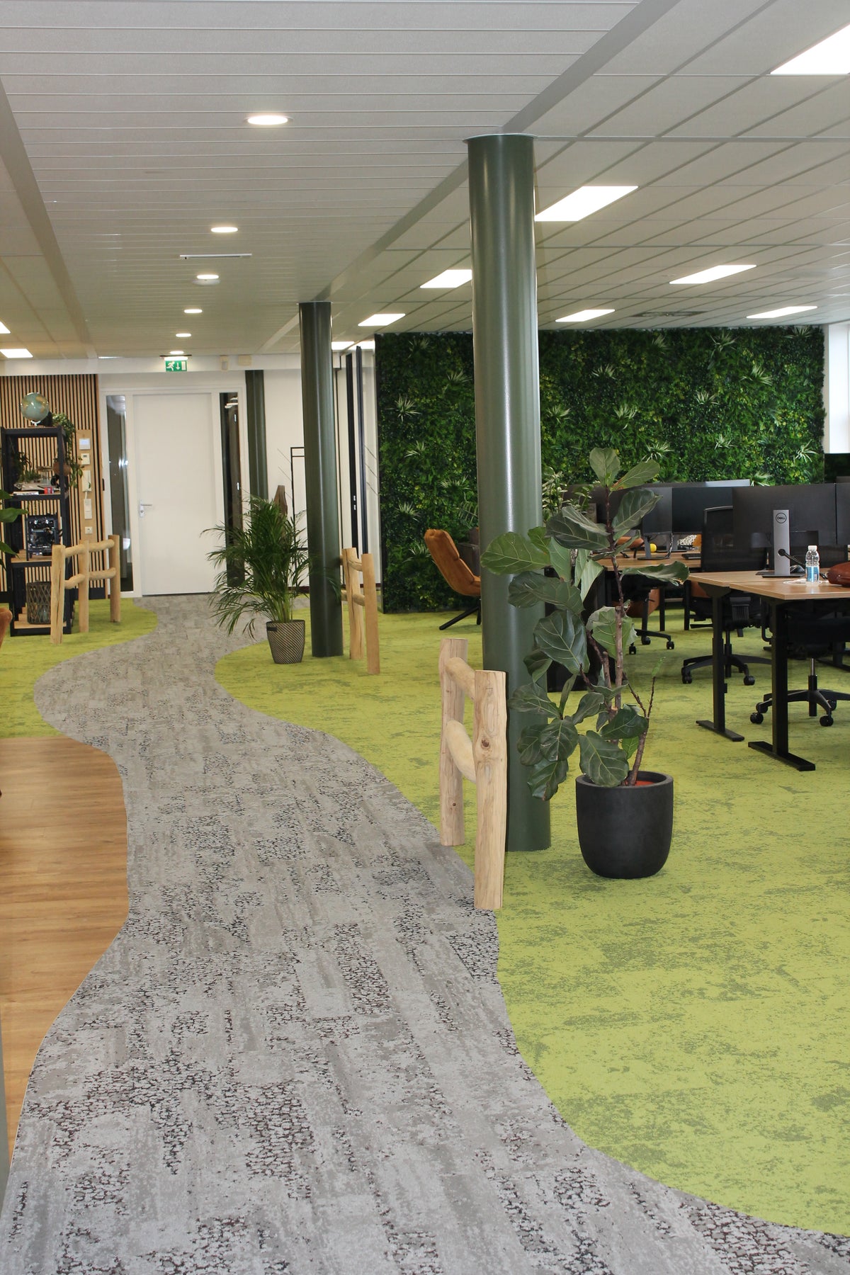 Kantoor met grijze tapijttegels als looppad door groene vloer, bureaus en planten