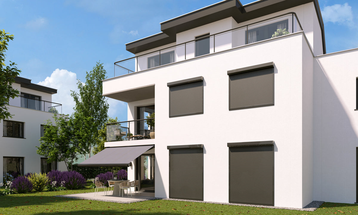 Wit appartementengebouw met grijze rolluiken voor de ramen en een knikarmscherm op het terras