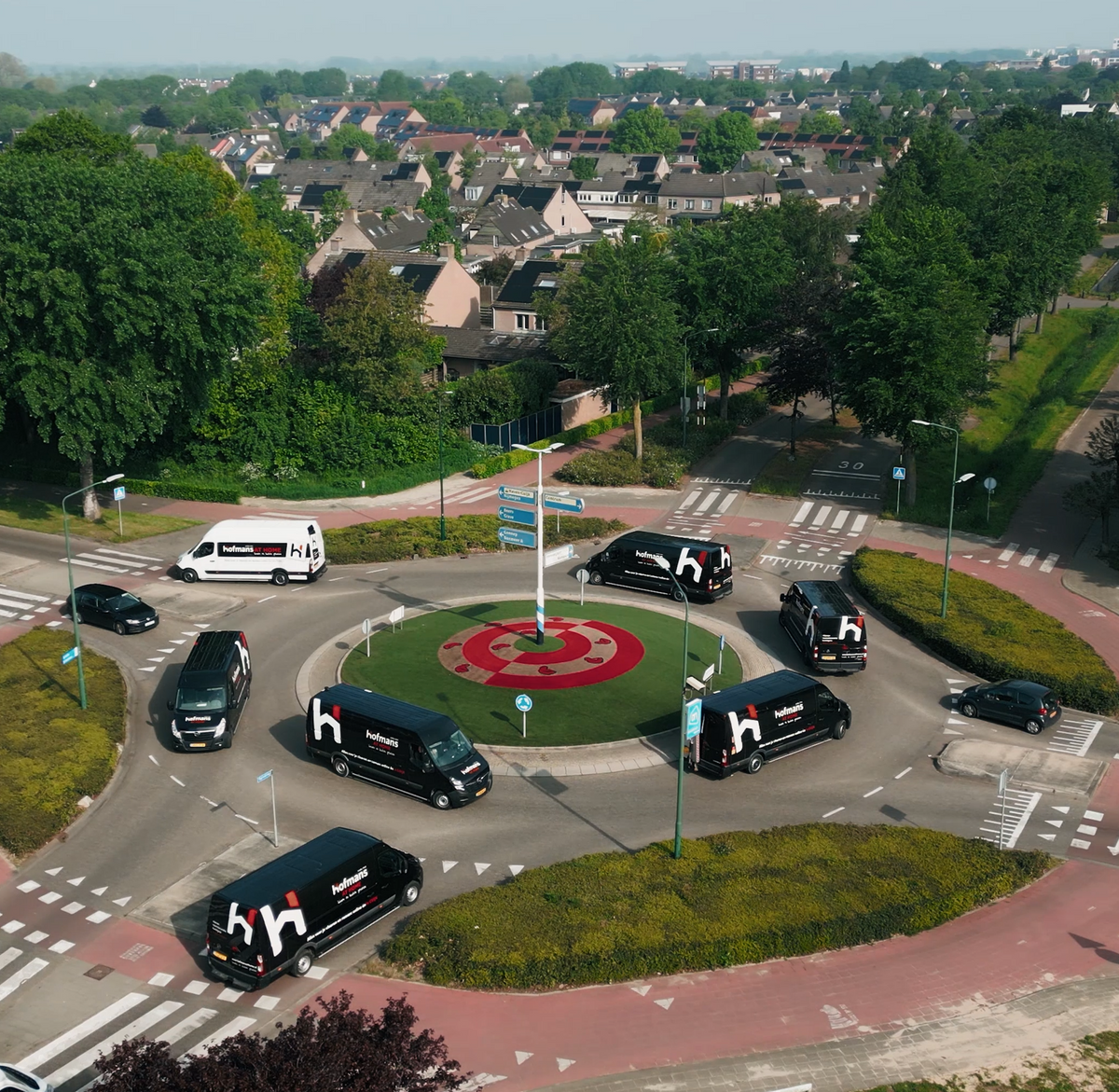 Luchtfoto van bedrijfsbusjes van Hofmans at Home rond een rotonde in Cuijk