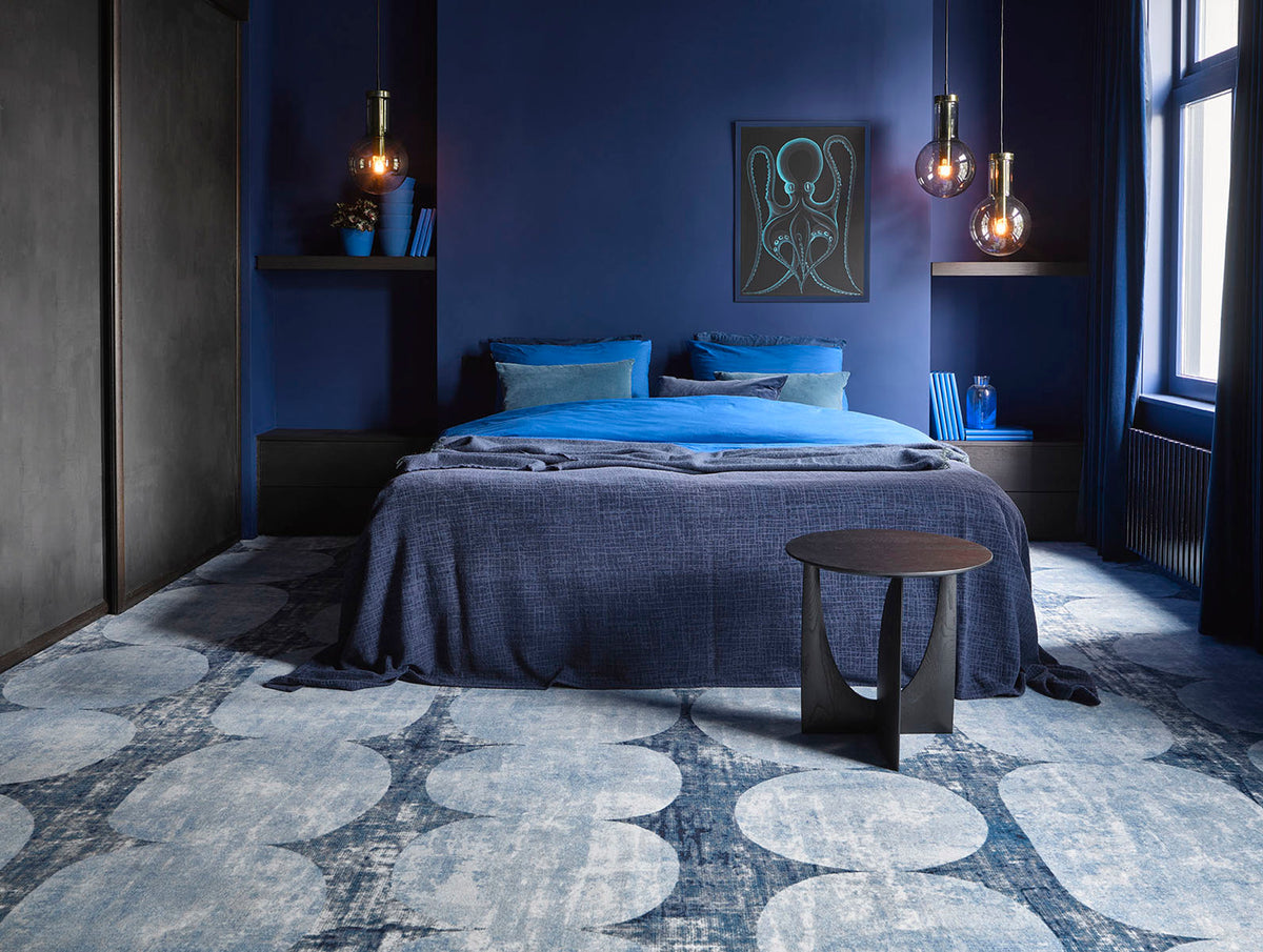 Blauwe slaapkamer met Desso tapijt in grafisch patroon, opgemaakt bed en hanglampen