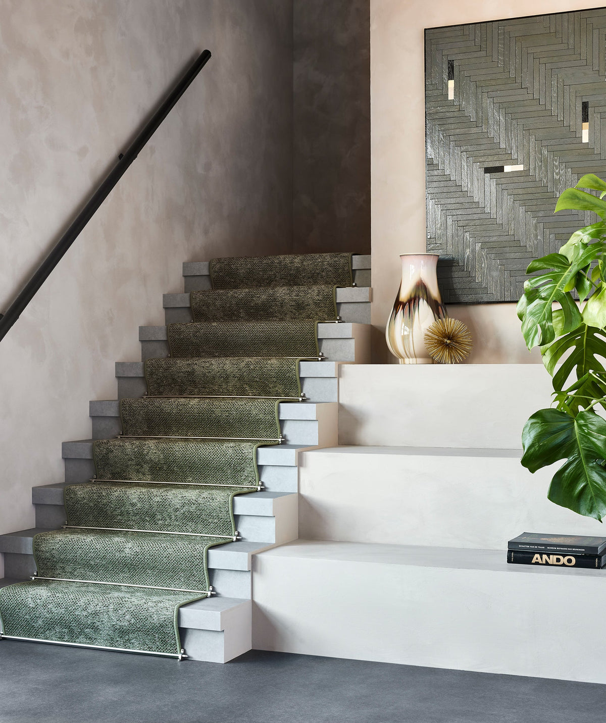 Moderne trap met groene Desso traploper, grijze treden en een stijlvol interieur met planten en decoratieve accessoires.
