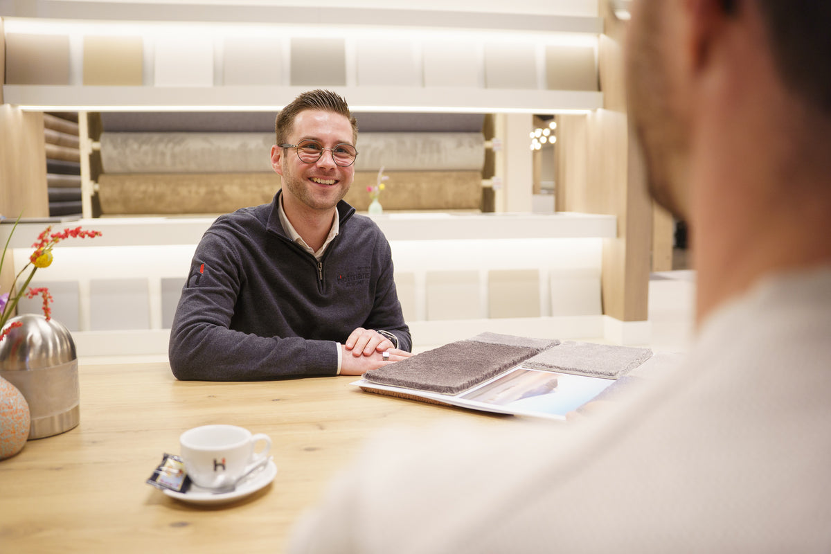 Interieuradviseur Luuk in gesprek over vloerkeuze met een klant in de showroom van Hofmans at Home