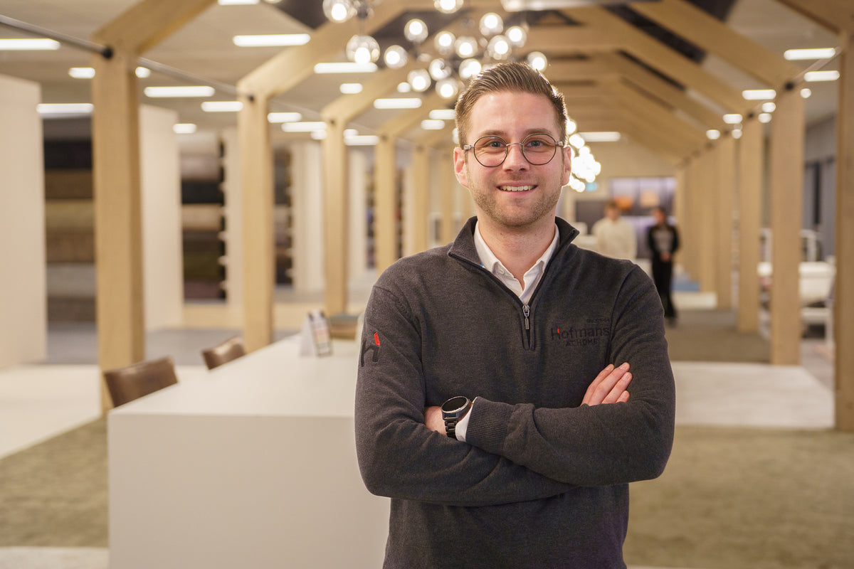 Adviseur Luuk met gekruiste armen in de moderne showroom van Hofmans at Home