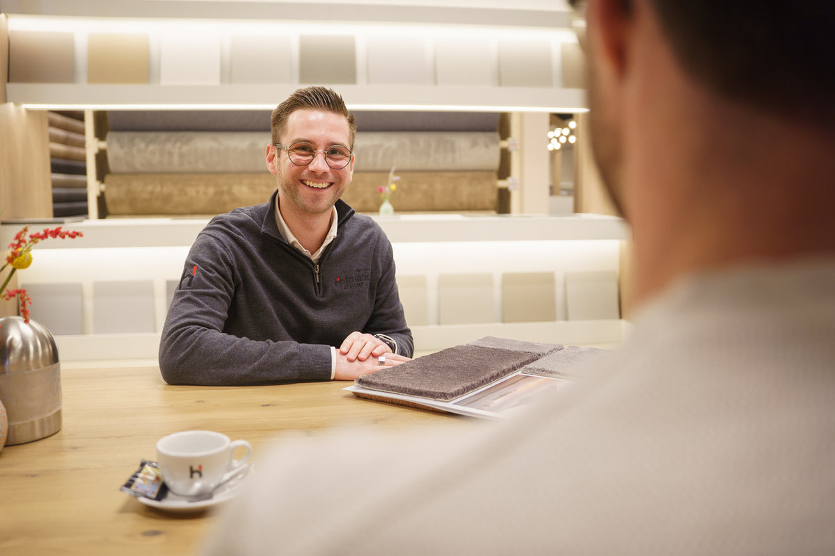 Interieuradviseur Luuk ontvangt een klant aan tafel voor vloeradvies bij Hofmans at Home