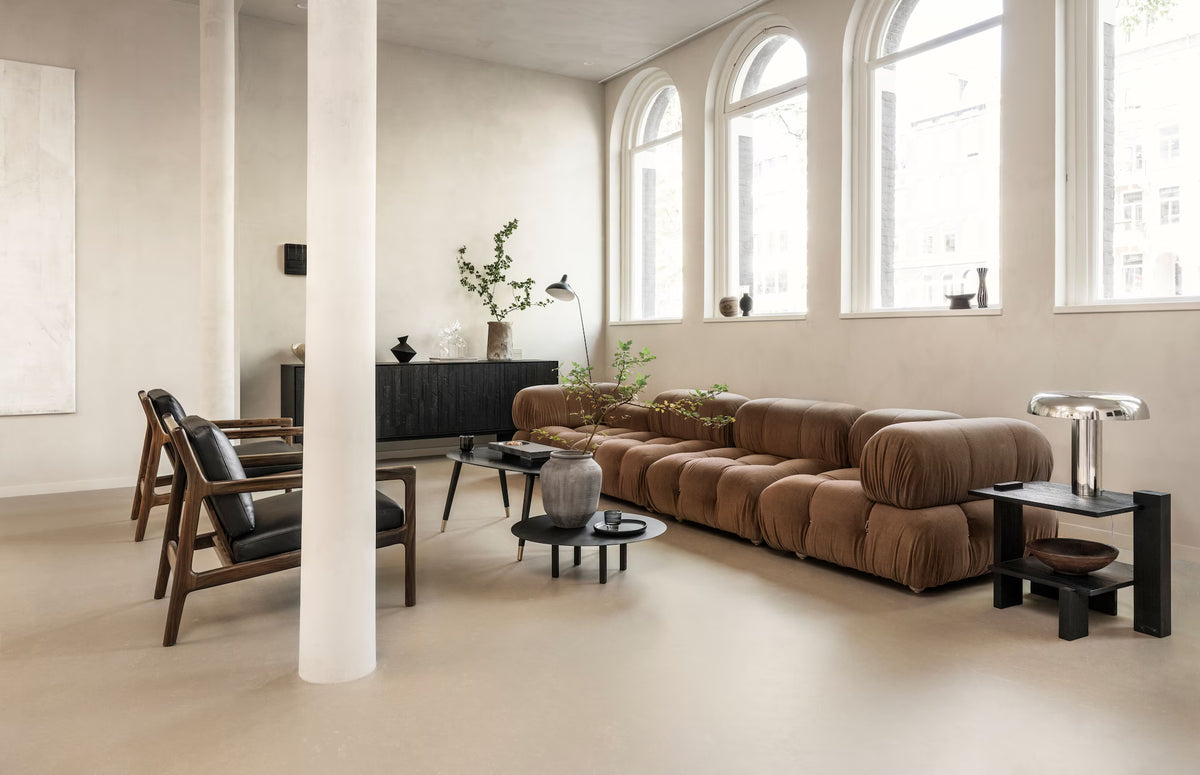 Lichte loft met naadloze marmoleum vloer, bruine bank en hoge boogramen