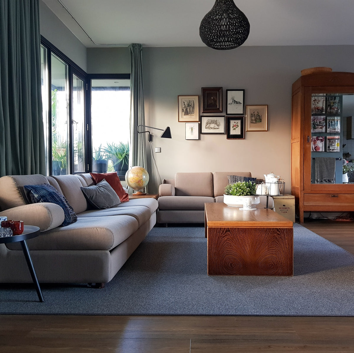 Woonkamer met donkere houten vloer, grijs vloerkleed, beige bank en houten salontafel