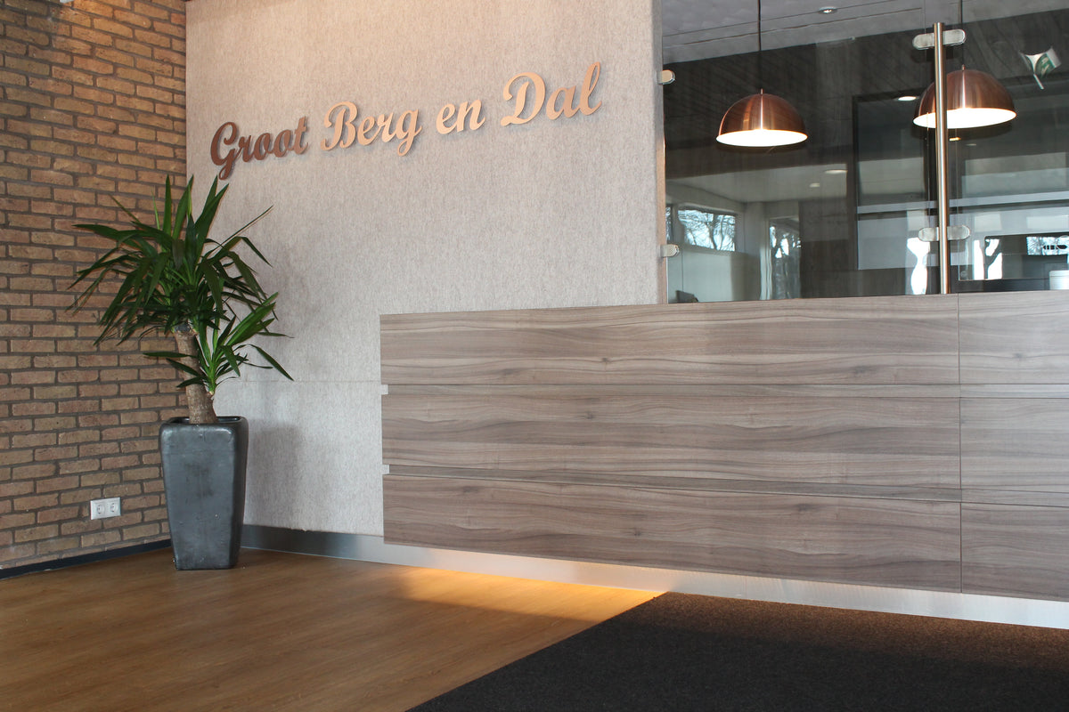 Entree van Groot Berg en Dal met houten balie, bakstenen wand en donkere vloer