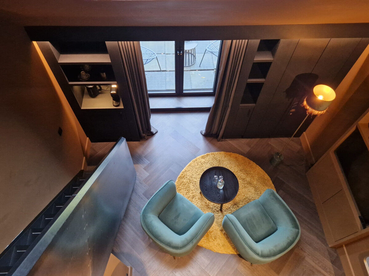 Hotelkamer van De Bungelaer van bovenaf met visgraatvloer en turquoise fauteuils