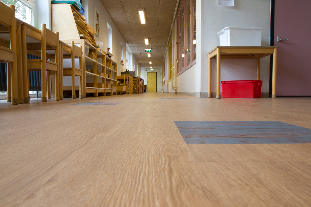 Schoolgang met lichte houtlook vloer, houten tafels, kasten en een rode bak