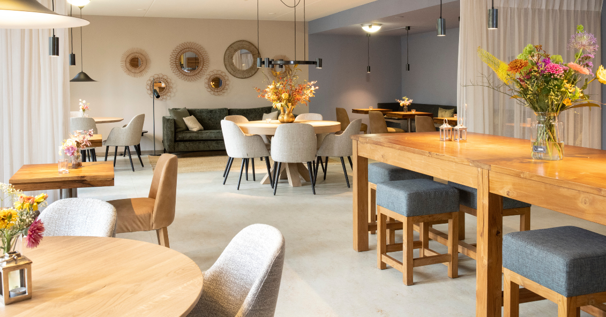 Restaurant met lichte vloer, houten tafels, grijze stoelen en spiegels aan de wand