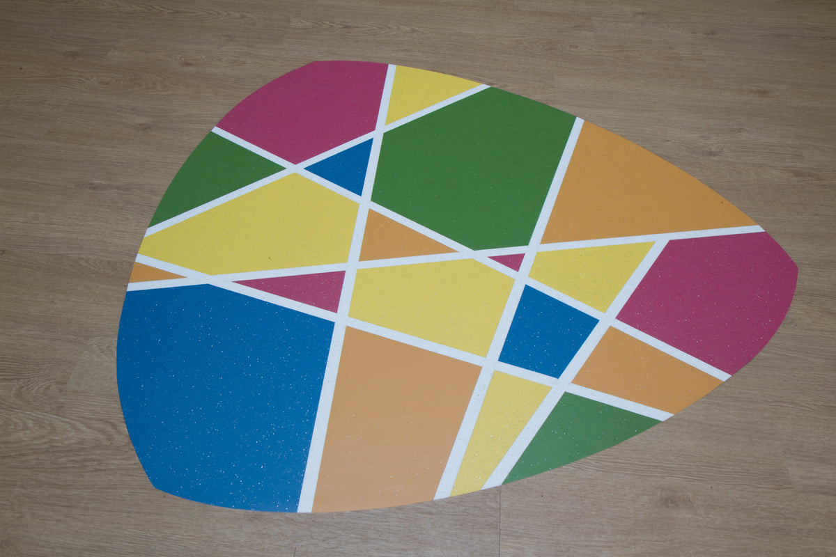 Speelse vloerinleg in vrolijke kleurvlakken op een houtlook vloer in een school