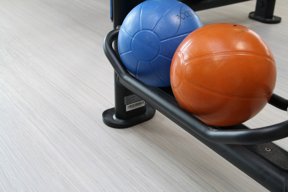 Close-up van een lichte sportvloer met medicijnballen in een rek