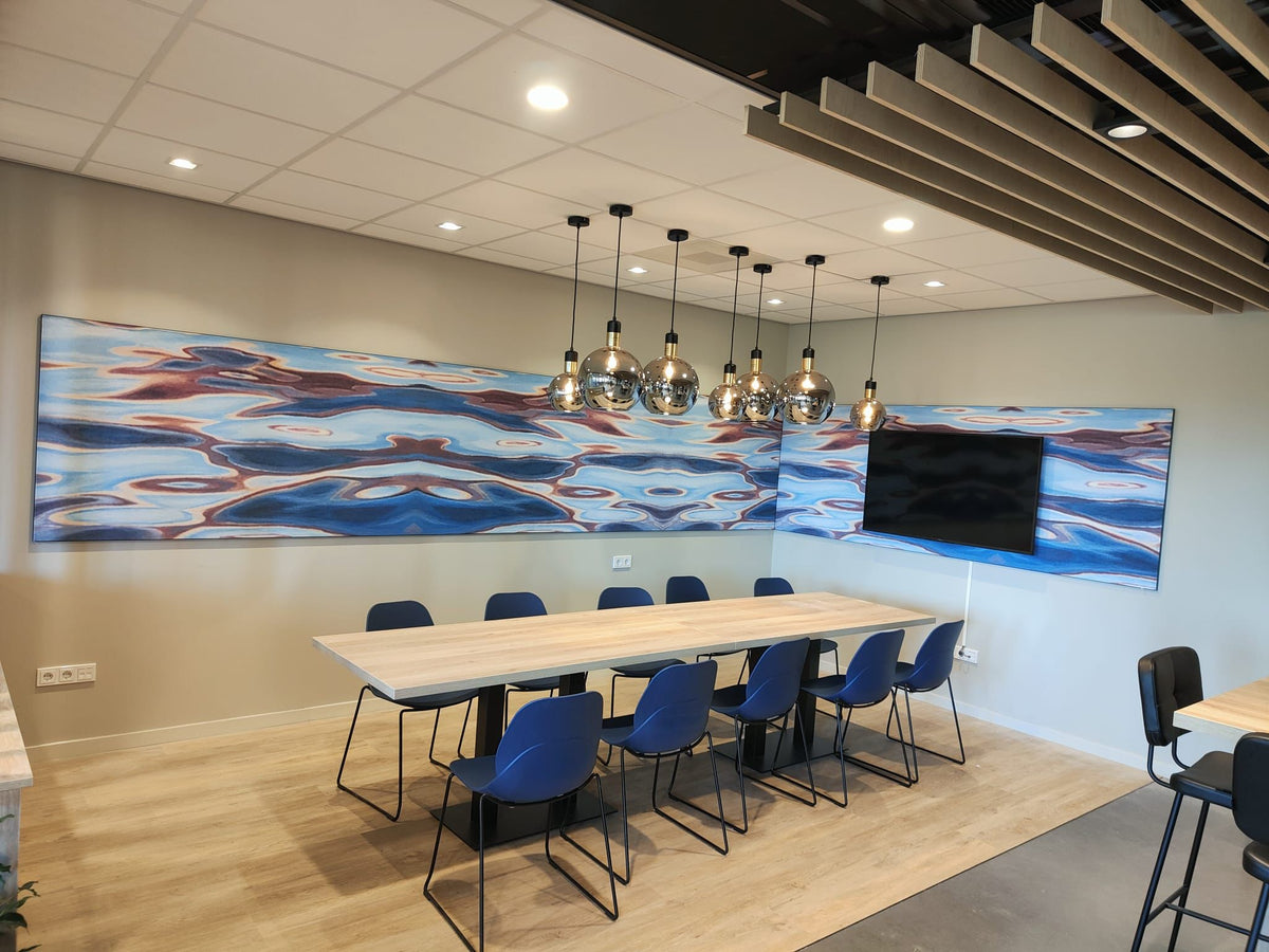 Vergaderruimte met lichte houten vloer, lange tafel, blauwe stoelen en hanglampen