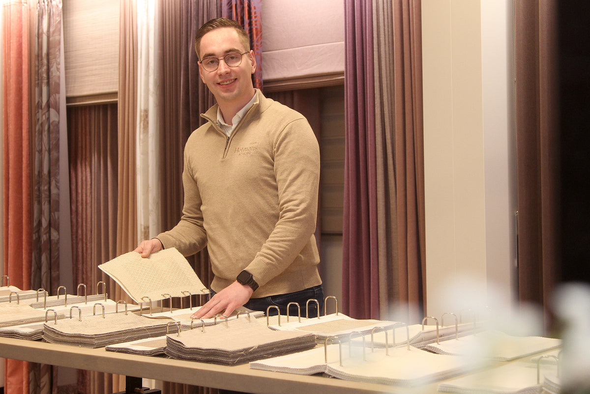 Showroom Hofmans at Home in Cuijk met spcialist Robert die gordijnstoffen presenteert in de raamdecoratieafdeling, onderdeel van de grootste showroom van Nederland.