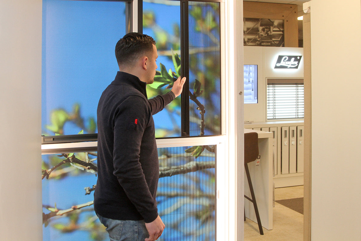 Showroom Hofmans at Home in Cuijk met demonstratie van horren en raamdecoratie door medewerker Sjoerd, onderdeel van de grootste showroom van Nederland.