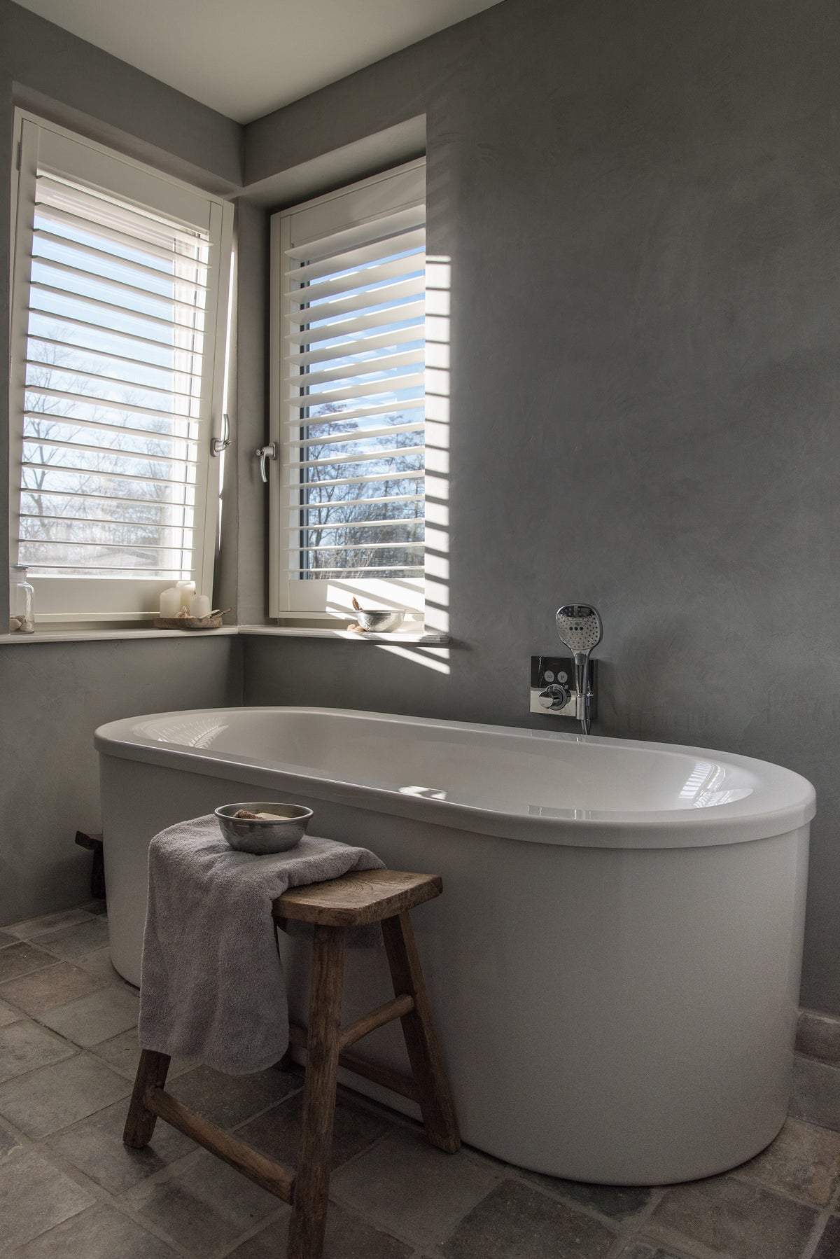 Badkamer met vrijstaand bad en witte shutters voor de ramen