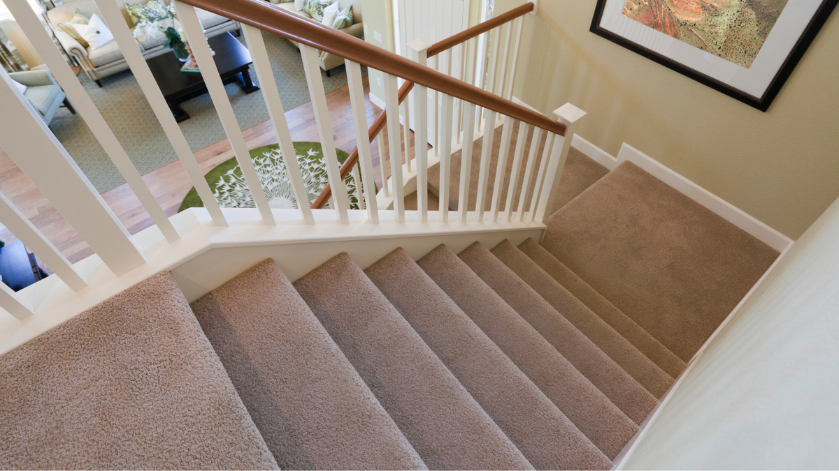 Trap met beige tapijt en witte balustrade, van bovenaf gezien
