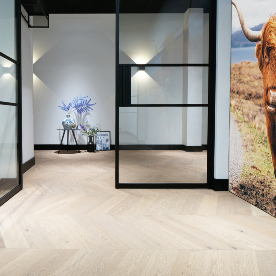 Moderne strakke woonkamer met een lichte pvc visgraat vloer. Moderne strakke plinten, onderdeel van de grootste showroom van Nederland.