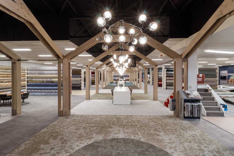 Tapijtafdeling in de showroom van Hofmans at Home met houten spanten, kroonluchters en tapijtrollen