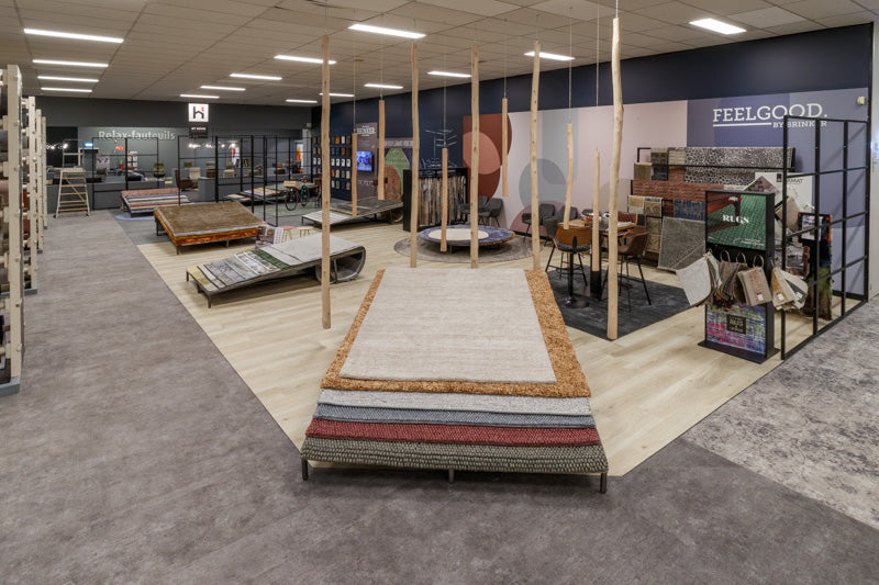 Vloerkledenafdeling in de showroom van Hofmans at Home met gestapelde kleden en presentaties